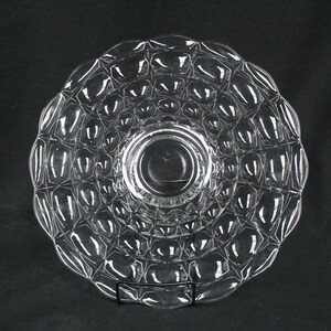 May include: A clear glass serving dish with a textured, bubble-like design. The dish has a raised center and a wide, flat rim.
