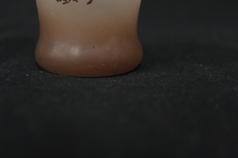 May include: A frosted glass vase with a brown gradient and a floral design. The vase has a rounded bottom and is sitting on a black surface.
