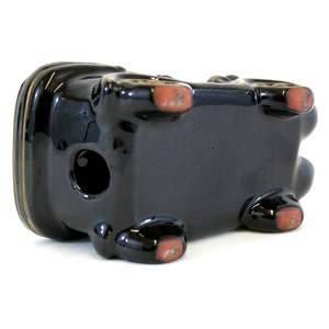 May include: Black ceramic planter shaped like a car with red accents on the bottom. The planter has a hole in the top for drainage.