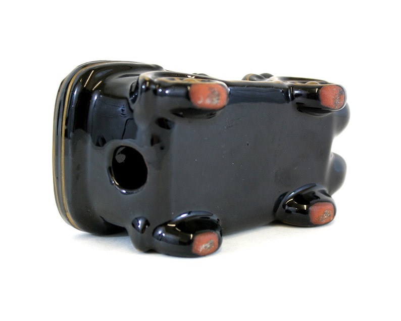 May include: Black ceramic planter shaped like a car with red accents on the bottom. The planter has a hole in the top for drainage.