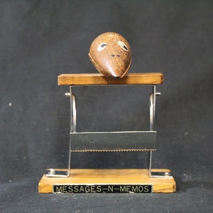 May include: A wooden memo holder with a carved wooden mouse on top. The holder has a metal frame and a wooden base with the words "MESSAGES - N - MEMOS" printed on it.