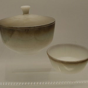 May include: A set of two white ceramic bowls with a brown ombre glaze. The larger bowl has a lid.