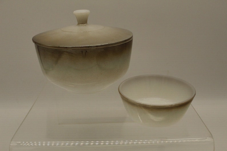 May include: A set of two white ceramic bowls with a brown ombre glaze. The larger bowl has a lid.
