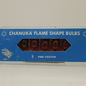 May include: A blue box with a Star of David on each end. The box contains 9 pre-tested Chanukah flame shape bulbs. The box says "Chanukah Flame Shape Bulbs" and "9 Pre-Tested".