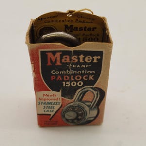 May include: Vintage Master Champ Combination Padlock 1500 in its original cardboard box. The box is tan and red with black text and a graphic of the padlock. The text on the box reads "Newly Improved! Stainless Steel Case."