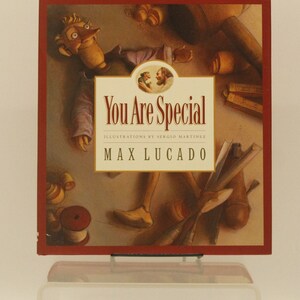 May include: A red book cover with a puppet illustration. The title of the book is "You Are Special" with the author's name "Max Lucado" printed below. The book cover features illustrations of a puppet, a workshop, and tools.