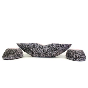 May include: A set of three ceramic bowls in a speckled black and pink design. The bowls are in the shape of a leaf and have a unique, organic look.