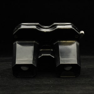 May include: A pair of black vintage binoculars with a textured finish. The binoculars have a rounded shape and are made of metal.