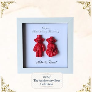 May include: A framed artwork with two red teddy bear figurines, a male in a suit and top hat, and a female in a dress. The text "On your Ruby Wedding Anniversary" and "John & Carol" are displayed. The bottom reads "Part of The Anniversary Bear Collection."