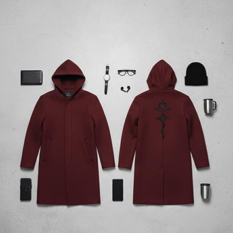 Puede incluir: Un abrigo con capucha color granate con un dise&ntilde;o bordado en negro en la espalda, exhibido con una cartera negra, tel&eacute;fono, reloj, gafas, auriculares, gorro y una taza. El abrigo es de estilo largo y entallado.