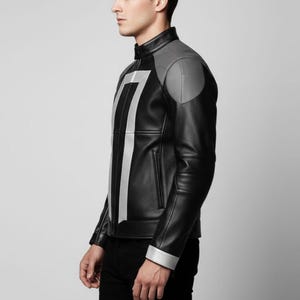May include: Black leather jacket with gray shoulder accents and a vertical silver stripe design. The jacket features a stand-up collar, silver cuffs, and a front zipper. The jacket is worn by a person.