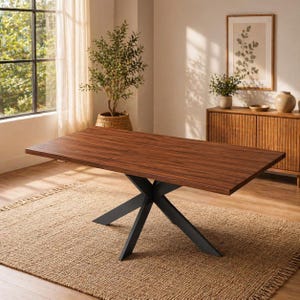 May include: A rectangular wooden dining table with a dark brown finish. The table has a black metal base with an X-shaped design. The table is set on a woven jute rug in a room with natural light.
