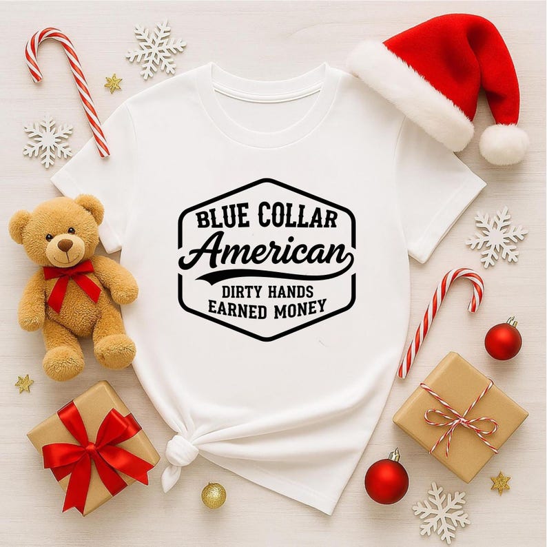 May include: White t-shirt with the text "BLUE COLLAR AMERICAN DIRTY HANDS EARNED MONEY" in a black hexagon design. The image includes a teddy bear, a Santa hat, wrapped gifts, candy canes, and Christmas ornaments.