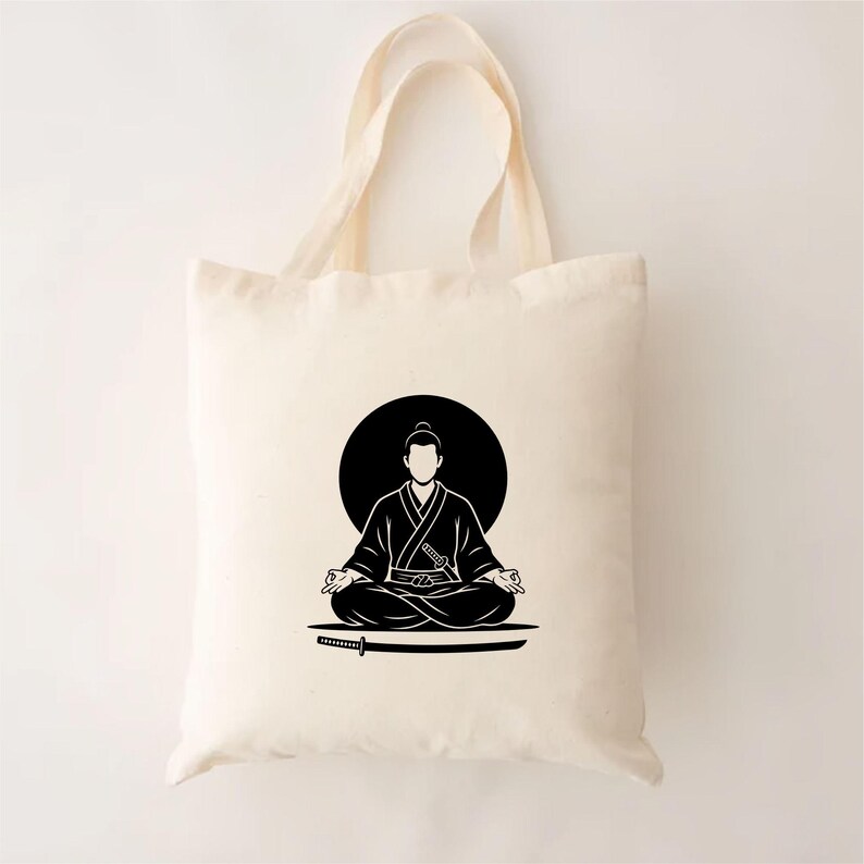 May include: Cream-colored tote bag featuring a black illustration of a meditating figure in a traditional Japanese outfit, with a katana sword below. The figure is set against a black circle, creating a minimalist design.