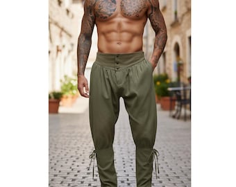 May include: Olive green pants with a high waist and button details. The pants have a loose fit through the legs, tapering to the ankles, and are secured with ties. The pants are made of a textured fabric.