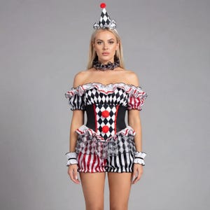 Könnte beinhalten: Ein Clownkostüm mit einem schwarz-weißen Rautenmuster, roten Akzenten und einem passenden Hut. Das schulterfreie Oberteil hat Rüschenärmel und die Shorts ein mehrschichtiges Design. Das Kostüm beinhaltet einen Choker und Handgelenkmanschetten.