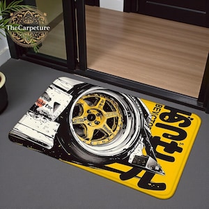May include: A rectangular doormat with a graphic of a car wheel with a gold rim and black tyre. The mat has a yellow background with Japanese text and a white and black design. The text "Regulator" is visible.