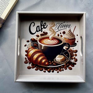 May include: A white wooden serving tray with a coffee-themed design. The tray features a cup of coffee, a croissant, a cupcake, and coffee beans. The words "Cafe Liocor" are written on the tray.