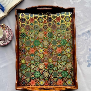 May include: A rectangular wooden serving tray with a colorful, intricate pattern. The tray's interior features a mosaic of red, green, yellow, and gold geometric shapes. The tray has a dark brown wooden frame with handles.