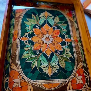 May include: Wooden serving tray with a stained glass design. The tray features a central orange flower with green leaves and a dark green background. The border is a mosaic of orange, brown, and green.