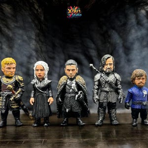 May include: Five detailed figurines of characters from a fantasy series, each with unique armor and clothing. The figures stand on a dark surface against a smoky backdrop. The figurines are approximately 10 cm tall.