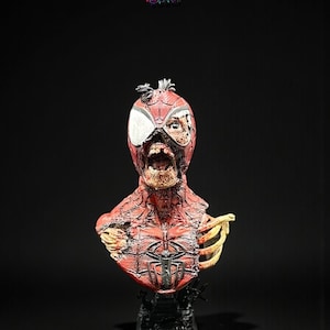 May include: A detailed bust of a zombie Spider-Man, featuring a red and black costume with exposed bone and decaying flesh. The bust is mounted on a black base, with the X-Art Studio logo in the top corner.