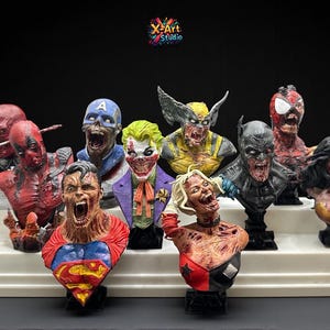 May include: A collection of superhero busts, including Deadpool, Superman, and Wolverine, displayed on a white tiered platform. Each bust features a detailed, zombie-like design with vibrant colors and intricate detailing. The X-Art Studio logo is visible.