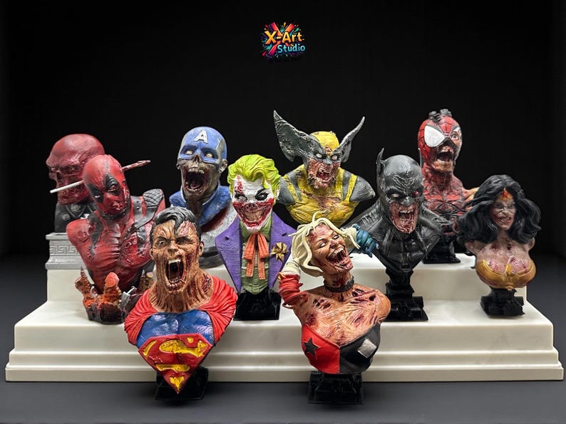 May include: A collection of superhero busts, including Deadpool, Superman, and Wolverine, displayed on a white tiered platform. Each bust features a detailed, zombie-like design with vibrant colors and intricate detailing. The X-Art Studio logo is visible.