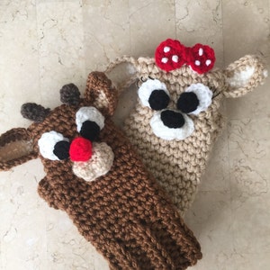 May include: Two crocheted hand puppets, one brown with a red nose and antlers, the other beige with a red bow and black eyes.