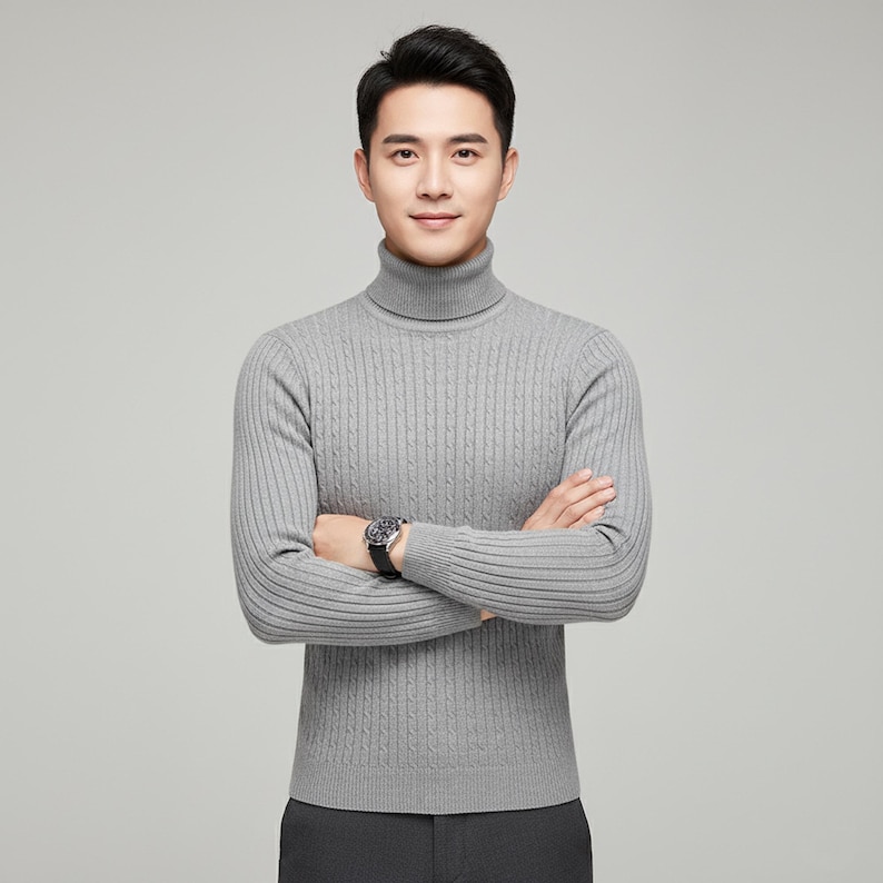 May include: A light gray turtleneck sweater with a cable knit design. The long-sleeved sweater has a ribbed texture and is worn with a black watch. The model is wearing dark gray pants.