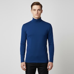 May include: A long-sleeved, royal blue turtleneck shirt. The shirt is made of a smooth, solid-colored fabric. The model is wearing black pants. The background is a plain, light gray.
