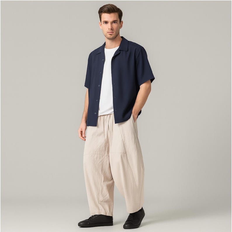 May include: A person wearing a navy blue short-sleeve button-down shirt over a white t-shirt, paired with beige wide-leg pants and black shoes. The outfit is simple and casual, suitable for everyday wear.