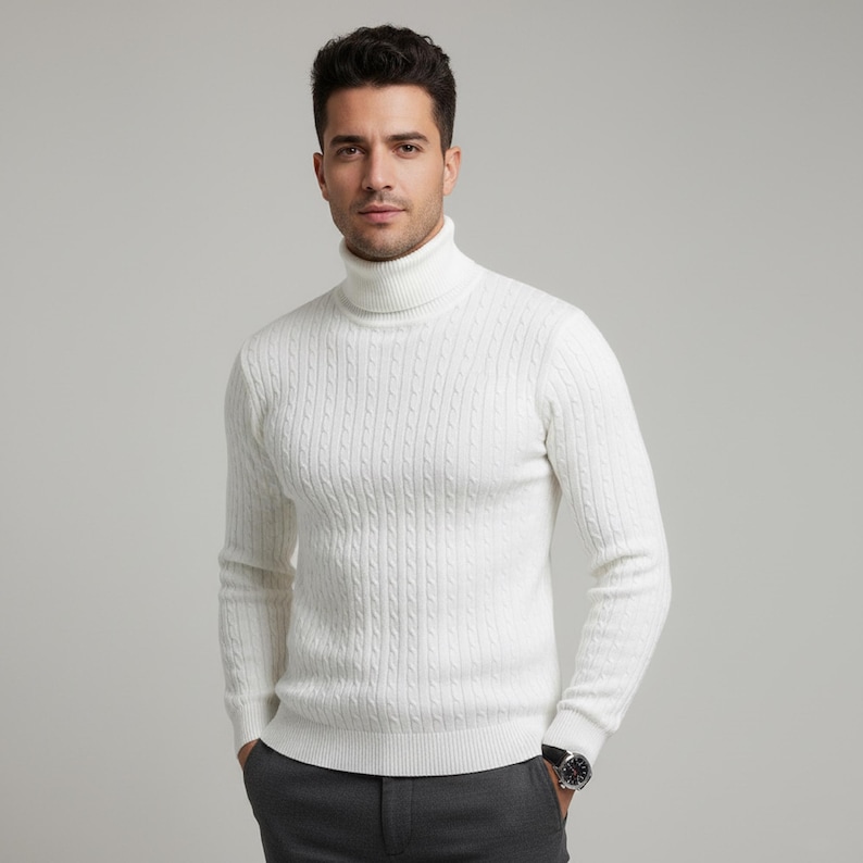 May include: A white cable-knit turtleneck sweater. The sweater has a ribbed texture and a high, folded collar. The sleeves are long, and the fit appears to be a classic style. The person is wearing a watch with a silver band and a dark face.
