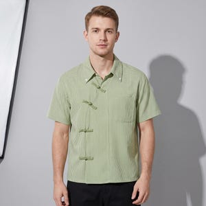 Può includere: Camicia verde chiaro a maniche corte con un piccolo motivo a quadri. La camicia presenta un'esclusiva chiusura con bottoni e un colletto classico. Realizzata in tessuto leggero, ha una tasca sul petto.