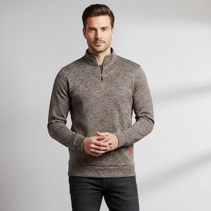 May include: A brown and grey textured pullover sweater with a quarter-zip neckline. The sweater has long sleeves and a small brown patch on the lower right side. The model is wearing black jeans.