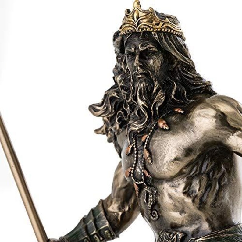 May include: A bronze-toned statue of a bearded man wearing a gold crown and a necklace. The statue has long, flowing hair and is holding a spear. The figure is muscular and detailed, with intricate carvings on the armor.
