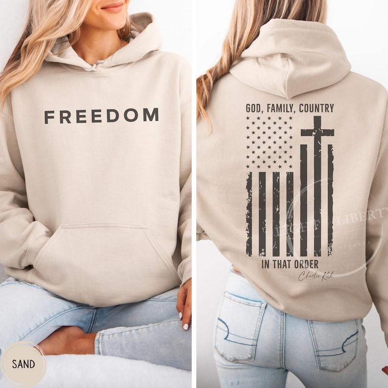 May include: A sand-colored hoodie with the word "FREEDOM" printed on the front. The back features an American flag design with a cross and the text "GOD, FAMILY, COUNTRY IN THAT ORDER".