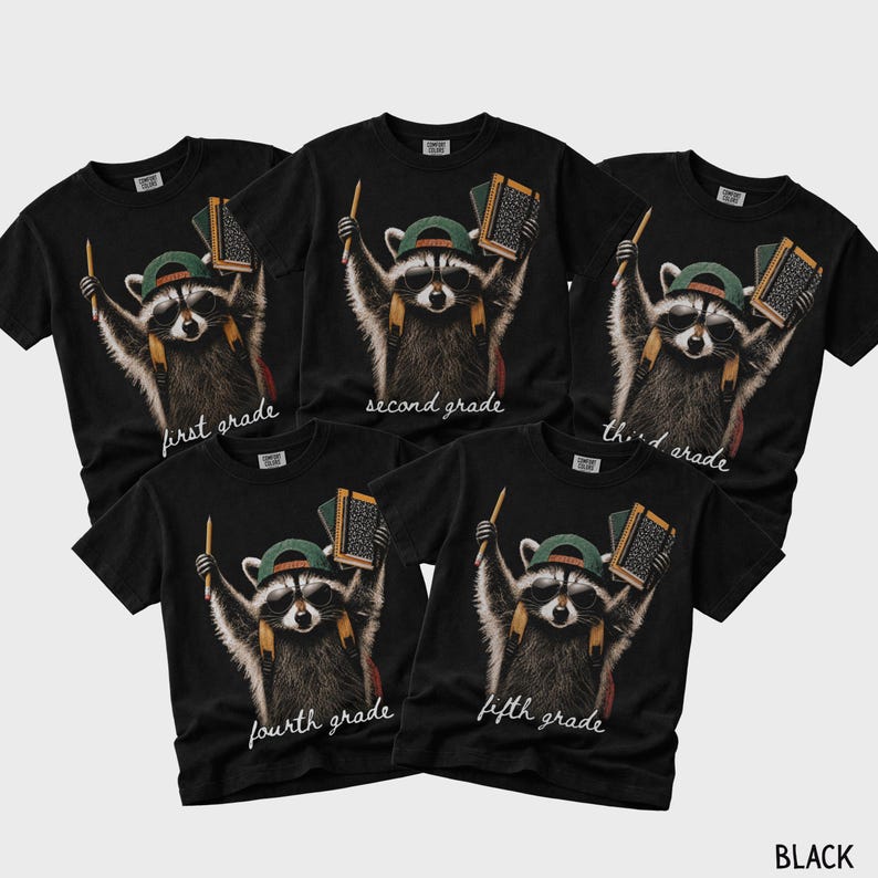 May include: Five black t-shirts featuring a graphic of a raccoon wearing sunglasses and a green baseball cap, holding a pencil and a notebook. Each shirt displays the text first grade, second grade, third grade, fourth grade, or fifth grade.