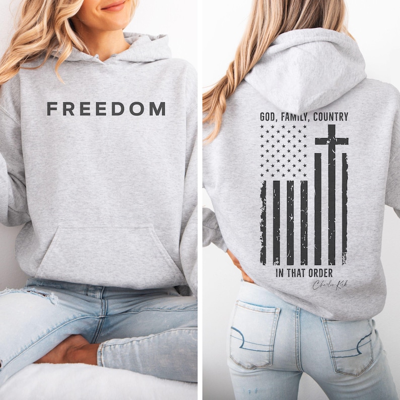 May include: Light gray hoodie with the word "FREEDOM" printed across the chest. The back features a distressed American flag design with a cross and the text "GOD, FAMILY, COUNTRY IN THAT ORDER".