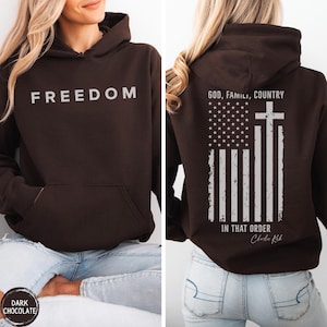 May include: Dark chocolate brown hoodie with the word "FREEDOM" printed in white on the front. The back features an American flag design with a cross and the text "GOD, FAMILY, COUNTRY IN THAT ORDER".