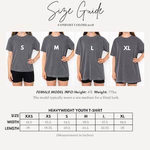 May include: A size guide for Comfort Colors 9018 heavyweight youth t-shirts. The image displays four charcoal grey t-shirts labelled S, M, L, and XL. A table provides width and length measurements in inches for sizes XXS through XL, alongside model info.