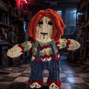 May include: A handmade crochet doll featuring bright orange yarn hair, a white face with dark stitched eyes and mouth, and a colorful sweater with red, white, and blue patterns. The doll wears blue yarn overalls and red shoes.