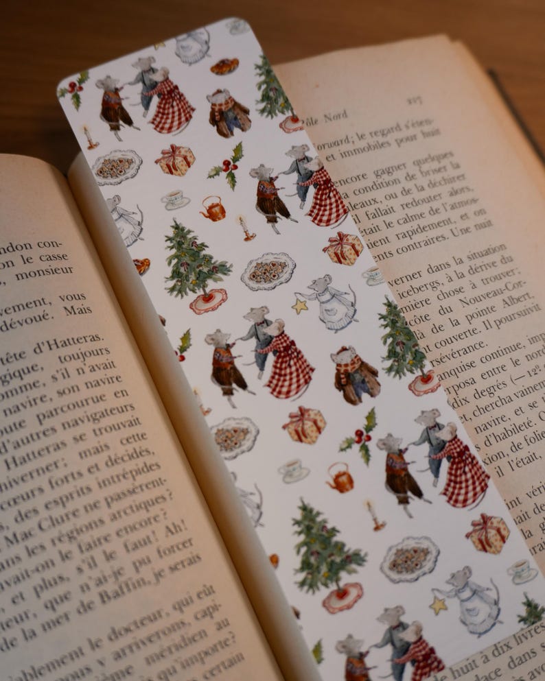 May include: A whimsical bookmark featuring a repeating pattern of dancing mice in festive attire, Christmas trees, gifts, and teacups. The bookmark is set against the backdrop of an open book, enhancing its literary theme.