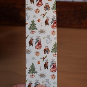 May include: A rectangular bookmark with a repeating pattern of mice in festive attire, Christmas trees, gifts, and food items. The mice are dressed in various outfits, including dresses and coats. The background is white.