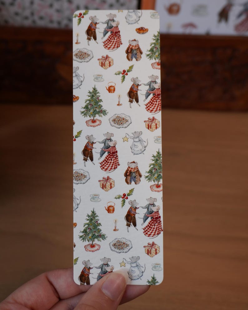 May include: A rectangular bookmark with a repeating pattern of mice in festive attire, Christmas trees, gifts, and food items. The mice are dressed in various outfits, including dresses and coats. The background is white.