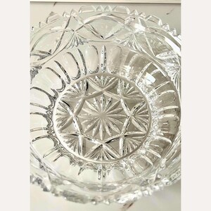 Peut inclure: Un saladier en verre taill&eacute; transparent avec un motif en &eacute;toile au centre et un bord festonn&eacute;. Le design complexe du bol pr&eacute;sente des formes de diamants et g&eacute;om&eacute;triques, refl&eacute;tant la lumi&egrave;re. Id&eacute;al pour servir ou d&eacute;corer.