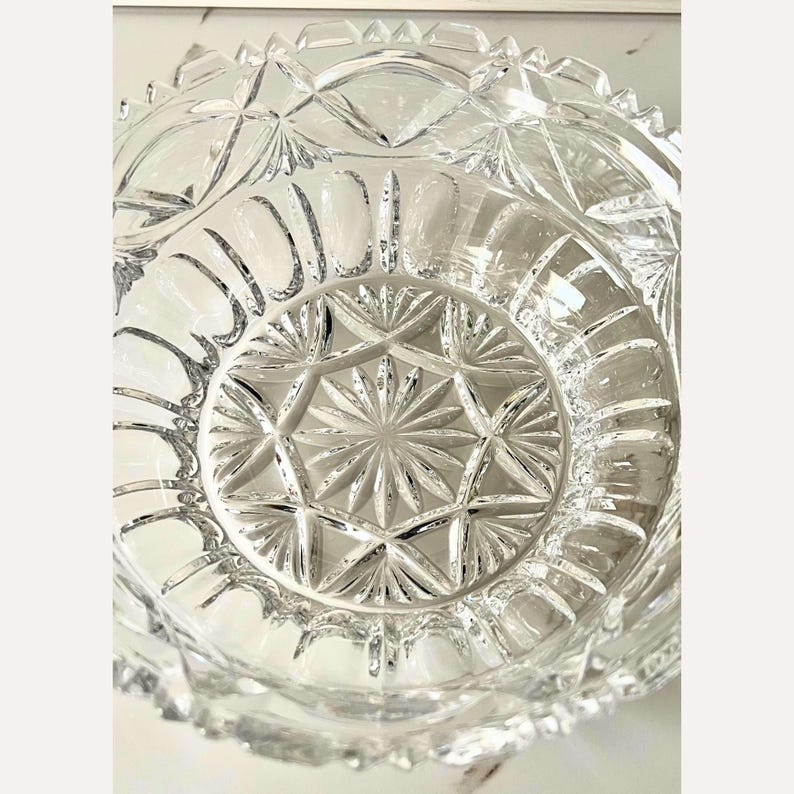 Peut inclure: Un saladier en verre taill&eacute; transparent avec un motif en &eacute;toile au centre et un bord festonn&eacute;. Le design complexe du bol pr&eacute;sente des formes de diamants et g&eacute;om&eacute;triques, refl&eacute;tant la lumi&egrave;re. Id&eacute;al pour servir ou d&eacute;corer.