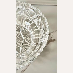 Peut inclure: Bol en cristal transparent avec un motif g&eacute;om&eacute;trique d&eacute;taill&eacute;. Le bol a un bord festonn&eacute; et un motif en &eacute;toile au centre. Le verre est tr&egrave;s r&eacute;fl&eacute;chissant, captant la lumi&egrave;re et cr&eacute;ant un effet scintillant. Probablement &agrave; des fins d&eacute;coratives ou de service.