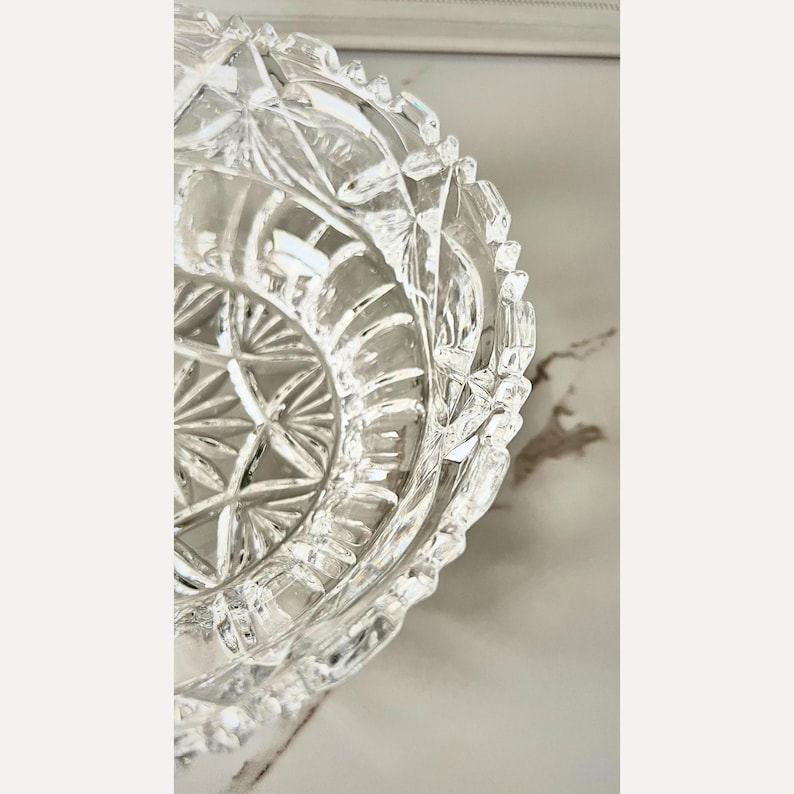 Peut inclure: Bol en cristal transparent avec un motif g&eacute;om&eacute;trique d&eacute;taill&eacute;. Le bol a un bord festonn&eacute; et un motif en &eacute;toile au centre. Le verre est tr&egrave;s r&eacute;fl&eacute;chissant, captant la lumi&egrave;re et cr&eacute;ant un effet scintillant. Probablement &agrave; des fins d&eacute;coratives ou de service.