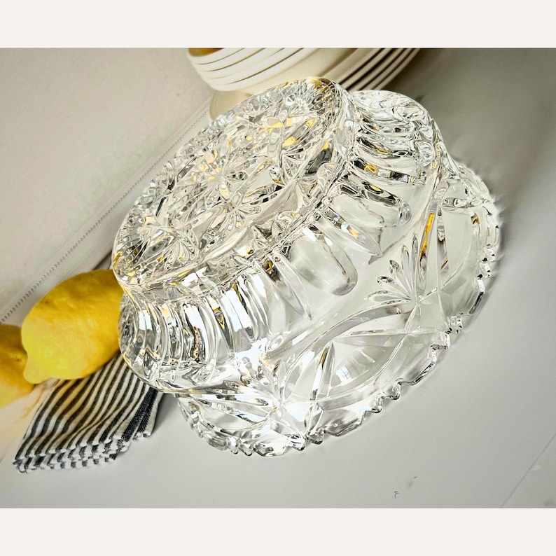 Peut inclure: Un bol en verre taill&eacute; transparent avec un motif floral et en &eacute;toile. Le bol est rond avec un bord festonn&eacute;. Le bol est pos&eacute; sur une surface blanche. Le bol est un objet d&eacute;coratif.